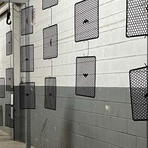 perforated metal material hanging on a powder coat line